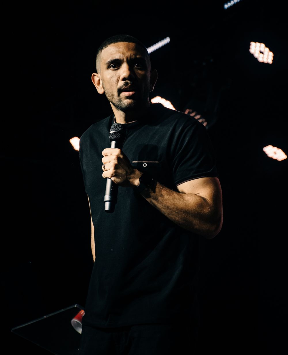 Carlos Jr pregando no palco, com microfone na mão
